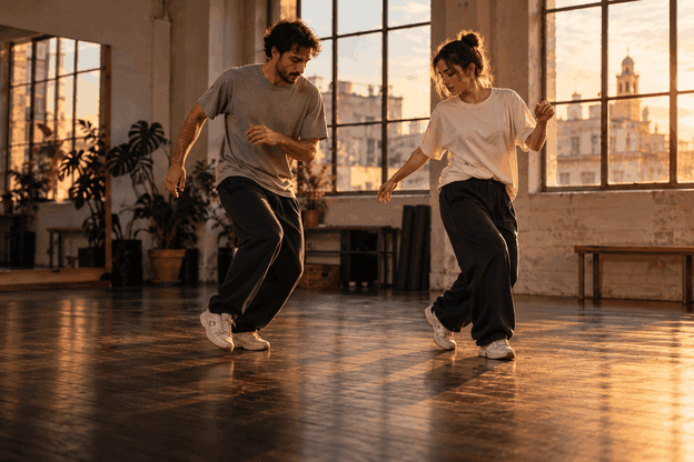 Dos bailarines ensayando pasos de house en una sala con suelo de madera
