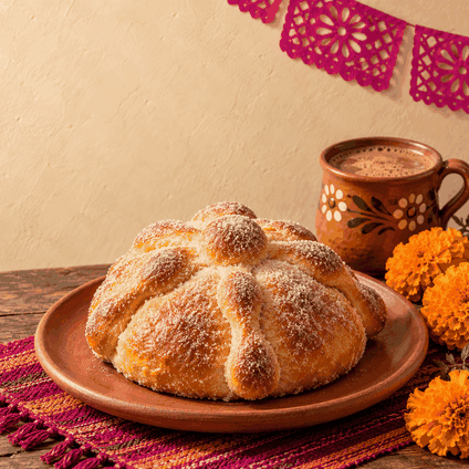 Pan de muerto con chocolate caliente, cempasúchil y papel picado para una publicación de temporada